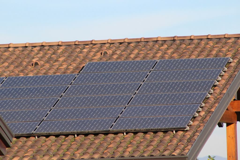 Solar panels on a terracotta tile roof in bright sun